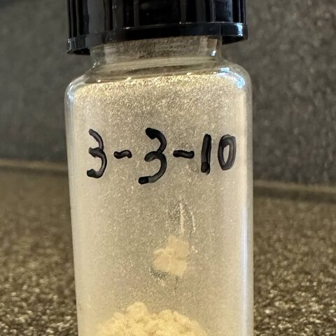 A small glass vial of white powder, labeled 3-3-10
